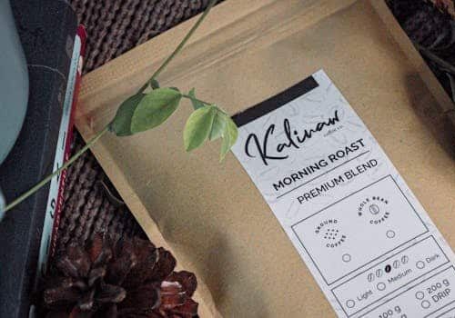 Aesthetic brown coffee pouch surrounded by pine cones and leaves, perfect for rustic themes.