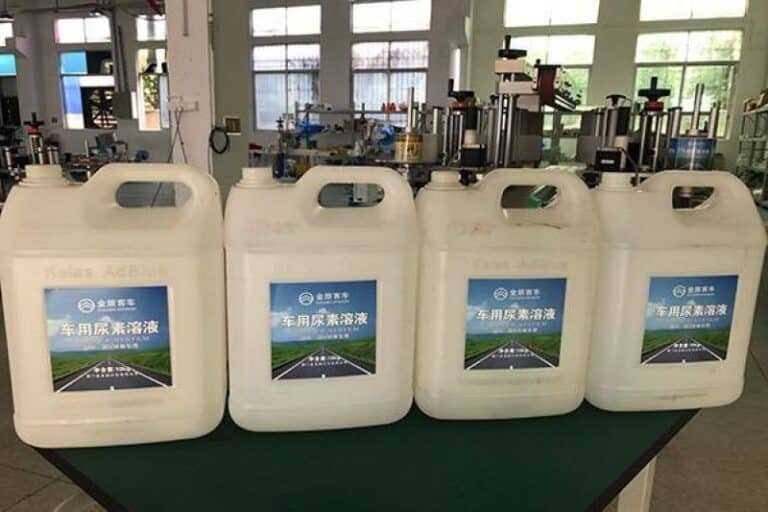 Labeled diesel exhaust fluid bottles (DEF / AdBlue) with automatic labeling machine applied for automotive emission control chemical packaging