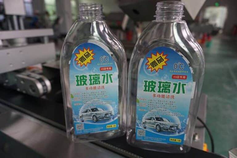 Labeled windshield wiper fluid bottles with automatic labeling machine applied for automotive chemical packaging