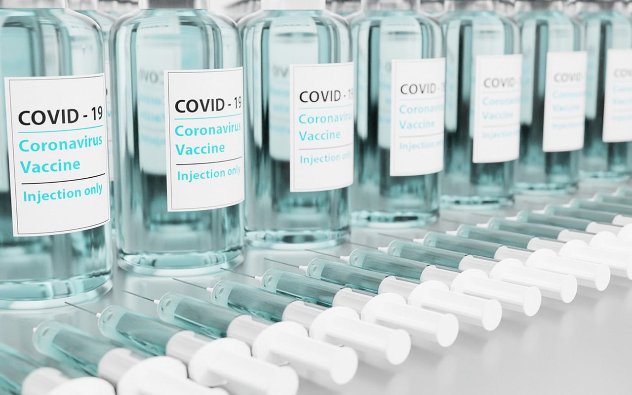 Labeled vaccine vials and syringes in COVID-19 vaccination medical packaging line, pharmaceutical labeling application