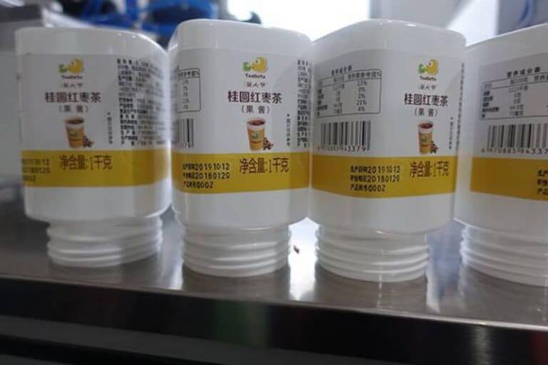 Labeled square beverage bottle with a wrap-around self-adhesive label