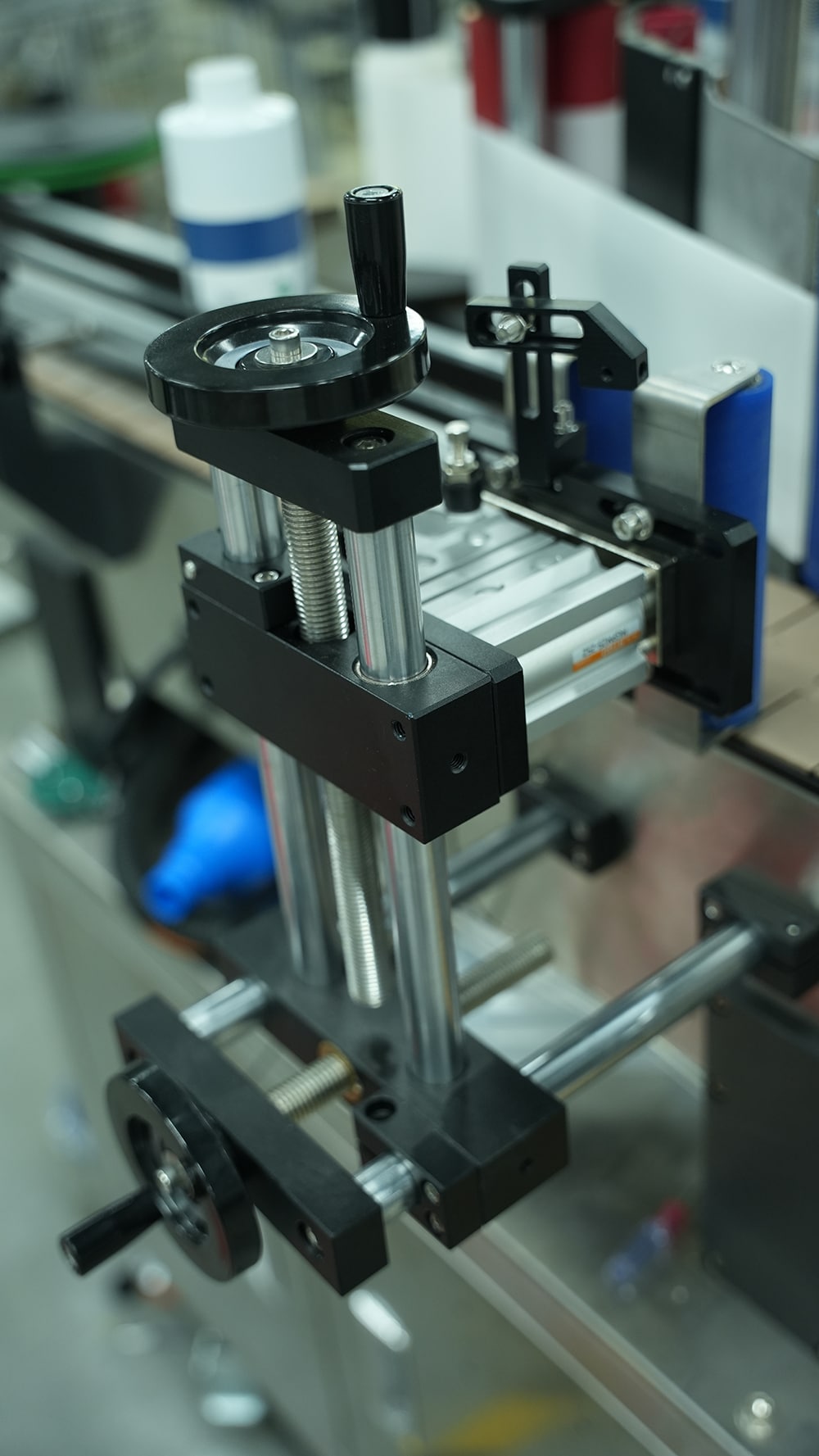 Tracking adjustment mechanism of an automatic wrap-around labeling machine for precise bottle positioning